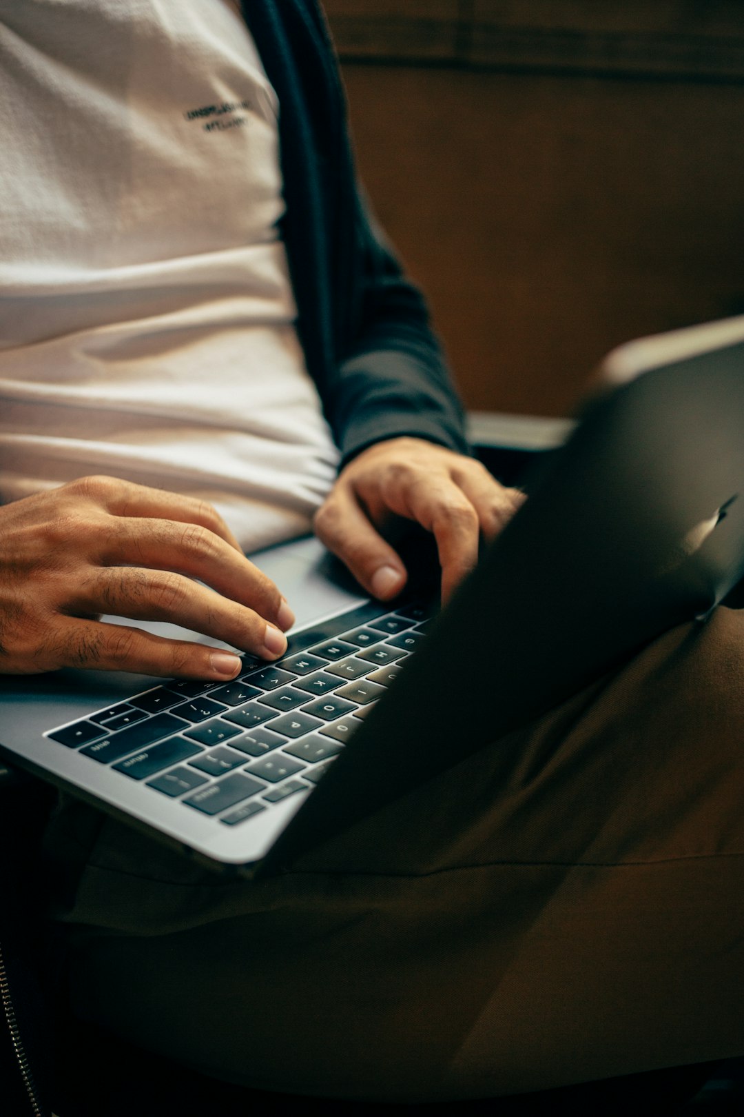 Close-up of hands typing on a MacBook keyboard, representing entering a secure password