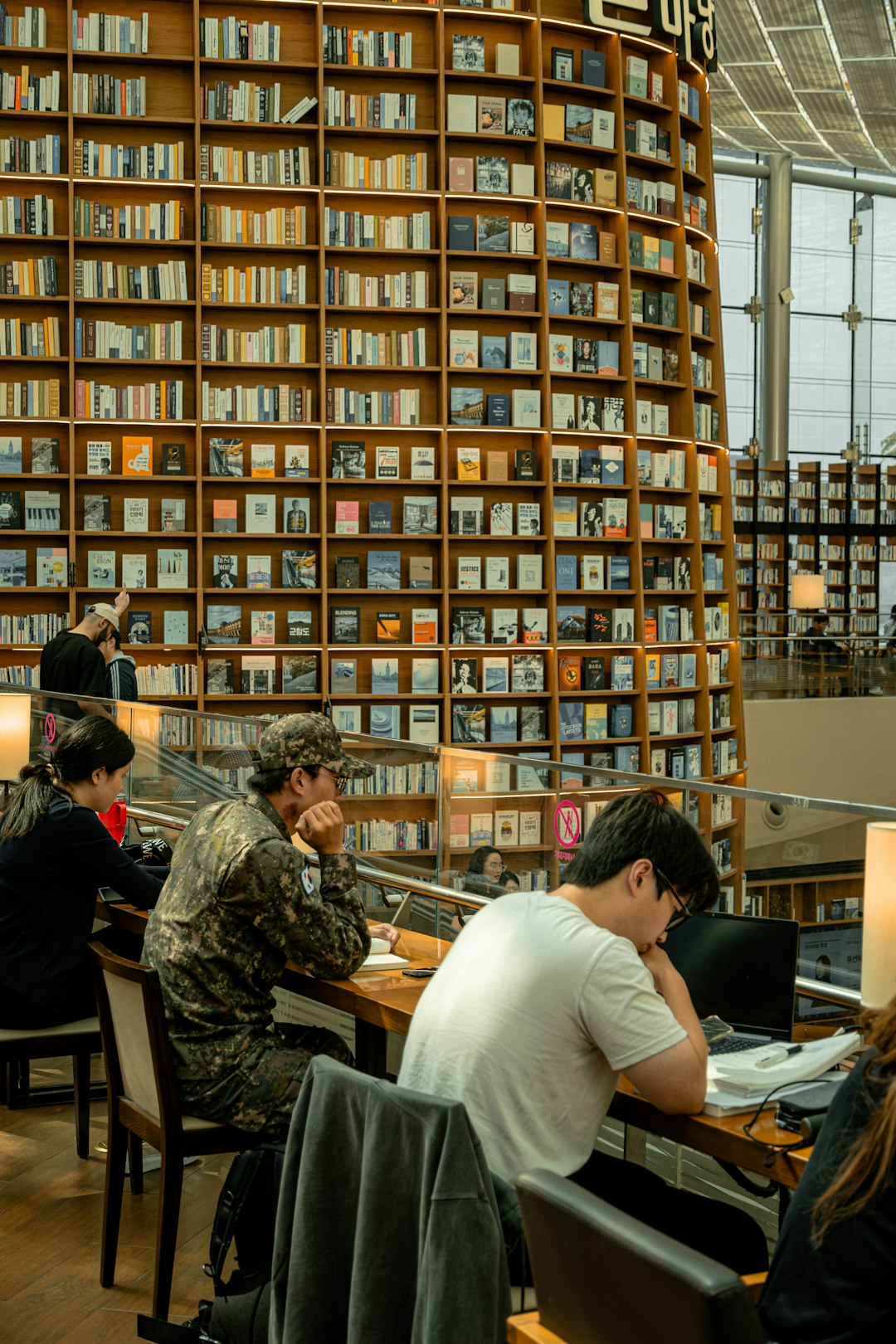 People studying at tables in a large library, representing students researching with AI tools