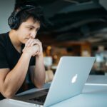 Student wearing headphones studying at a laptop, representing AI-assisted learning